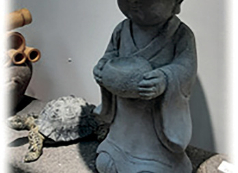 Statue of a monk in meditation, wearing a hat